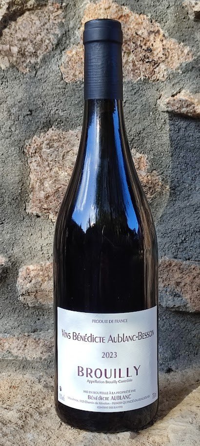 Bouteille de Brouilly 2023, Vins Bénédicte Aublanc-Besson, posée devant un mur de pierre